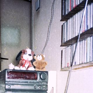 Vintage electronics and stuffed toys on cluttered shelf.