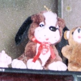 Vintage electronics and stuffed toys on cluttered shelf.