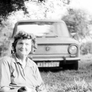 Woman sitting on picnic blanket outdoors with cat.