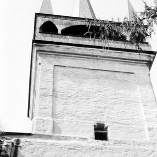 Stone tower with pointed spires and arched openings.