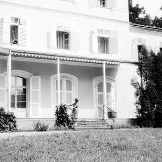 Classic mansion exterior with person gardening.