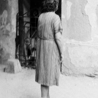 Young girl standing near old stone doorway.