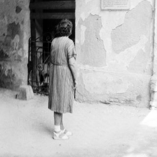 Young girl standing near old stone doorway.