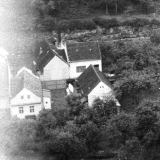Rural village by lake with houses and trees.