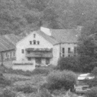 Historic bridge spanning river with forested hills.