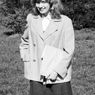Woman in 1960s-style coat and skirt outdoors.