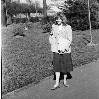 Woman in 1960s-style coat and skirt outdoors.