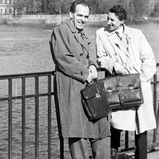 Two men posing by a river bridge.