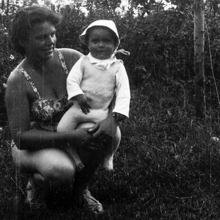 A woman holding a smiling infant outdoors.