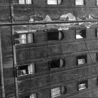 Aged multi-story building with weathered facade and broken windows.