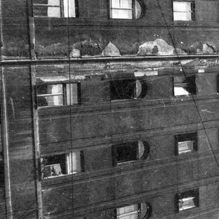 Damaged multi-story building facade with large cracks.