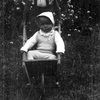 Two children sitting on a swing outdoors.