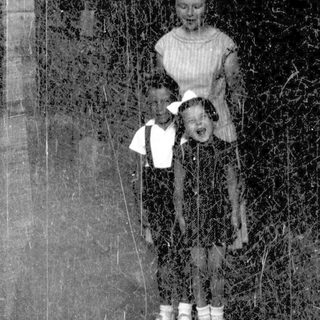 Two figures in vintage clothing standing in snowy forest.