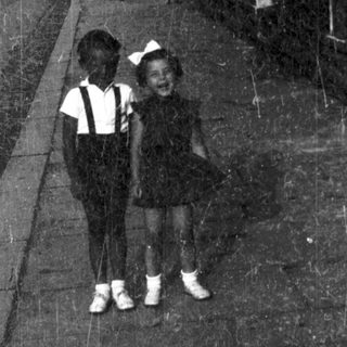 Two children walking on a dimly lit path.