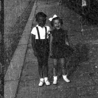 Two children walking on a dimly lit path.