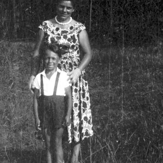 Two people standing outdoors in natural light.
