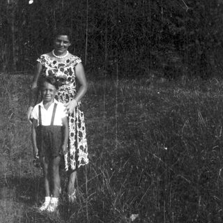Two people standing outdoors in natural light.
