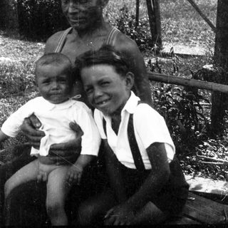 Family portrait with elderly man and two children outdoors.