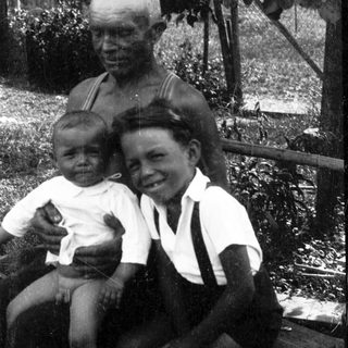 Family portrait with elderly man and two children outdoors.