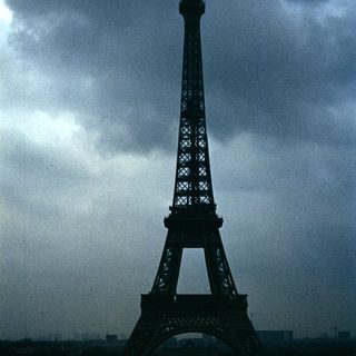 Eiffel Tower silhouetted against stormy sky.