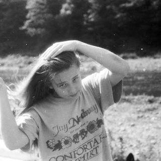 Girl laughing outdoors in windy conditions.