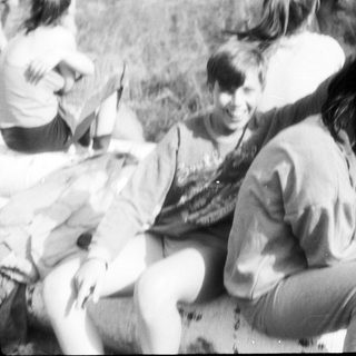 Group of people sitting outdoors, engaged in conversation.
