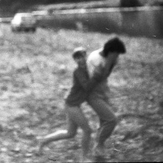 Two individuals running through a muddy, rural area.