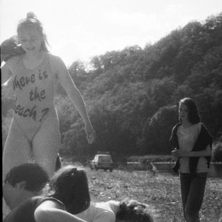 People protesting near water with sign reading "Where is the beach?"
