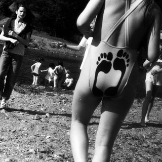 People at outdoor gathering near waterfront, wearing 1970s-style swimwear.
