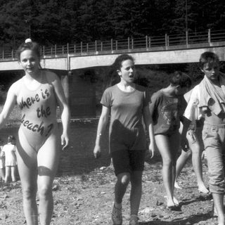 Person in bikini holding sign near water.
