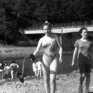 Person in bikini holding sign near water.