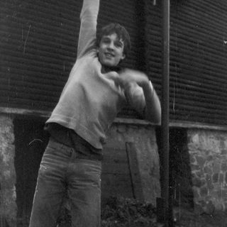 Young person climbing or hanging from a pole.