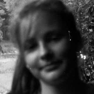 Blurry black-and-white photo of smiling person outdoors.