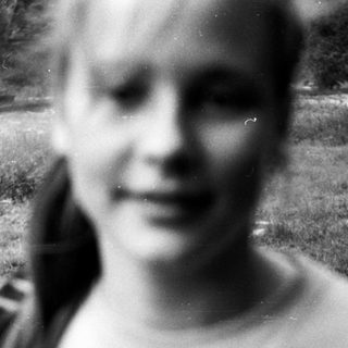 Blurry black-and-white photo of smiling person outdoors.