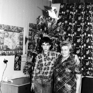 Family posing with Christmas tree indoors.