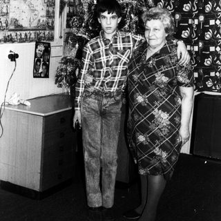 Family posing with Christmas tree indoors.