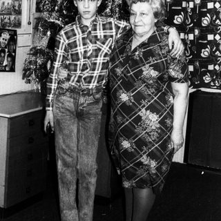 Family posing with Christmas tree indoors.