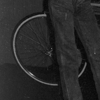 Young person holding envelope near bicycle in cluttered room.