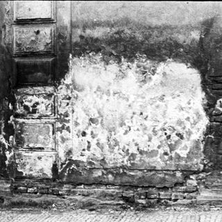 Damaged wall with exposed brick and plaster.