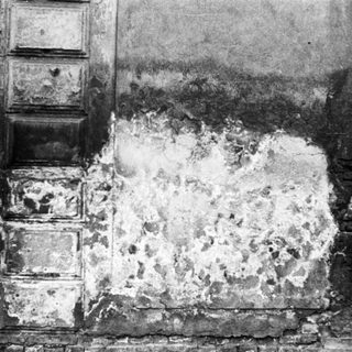 Damaged wall with exposed plaster and brick.