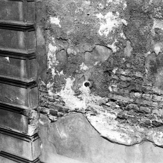Damaged wall with exposed brick and plaster deterioration.