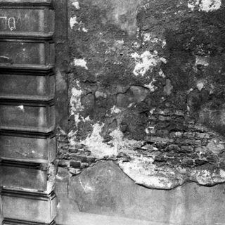 Damaged wall with exposed brick and concrete deterioration.