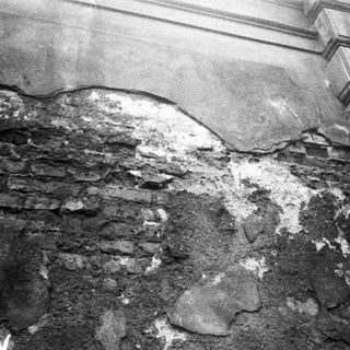 Damaged wall with exposed brick and plaster cracks.