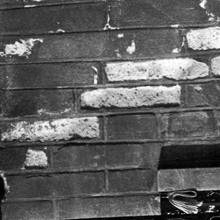 Damaged brick wall with white mortar deterioration.
