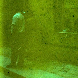 Worker cleaning large yellow stone wall.