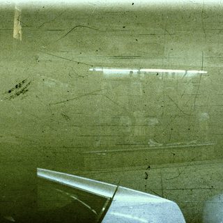 Damaged green bathroom wall with exposed cracks.