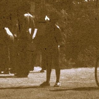 Vintage photo of people walking near bicycles.