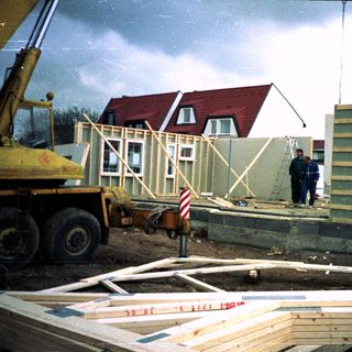 Construction site with wooden house frame under assembly.