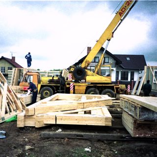Construction site with crane lifting wooden beams.