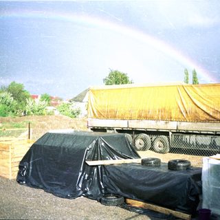 Construction site with truck, tarps, and rainbows after rain.